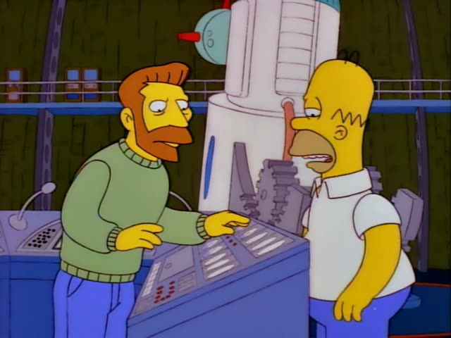 Homer stands at a control panel beside a bearded man with orange hair and a green sweater, who gestures with one raised…