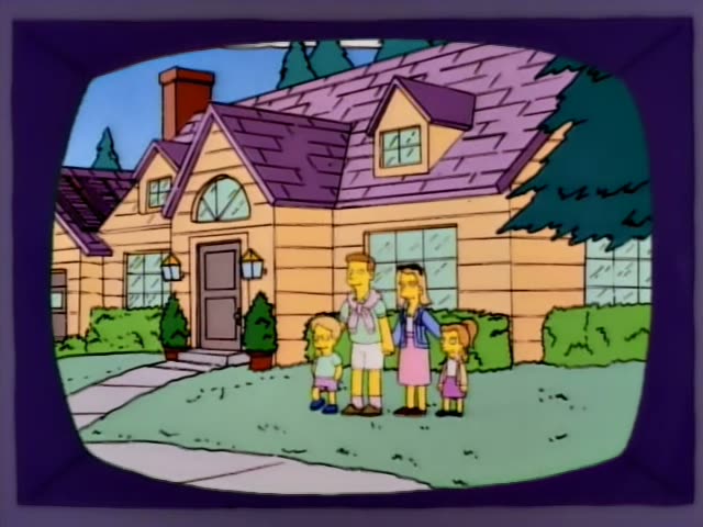 A family of four stands in front of a yellow house with a purple roof, with a man in a white shirt and light shorts…