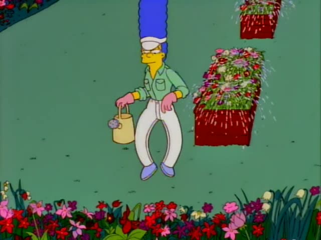 Marge Simpson wears a green shirt, white pants and pink gardening gloves while tending the lawn of a sunny estate