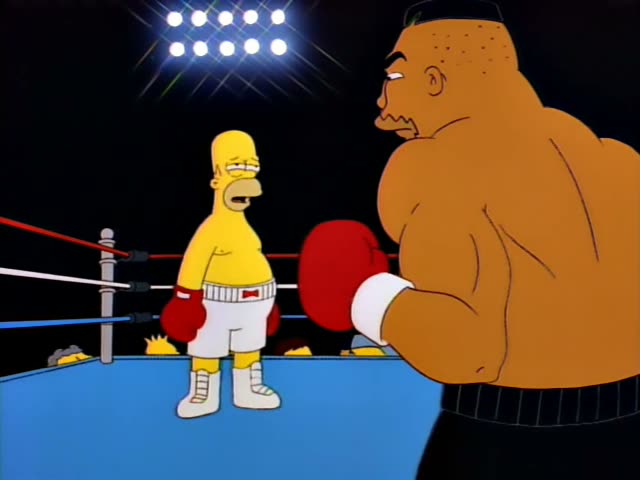 Homer Simpson stands in a brightly lit boxing ring with blue canvas and red, white and blue ropes, facing a huge…