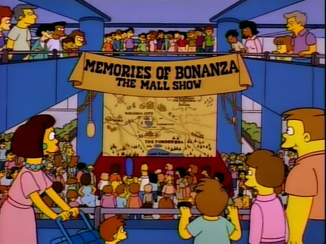 Homer and Marge stand among a dense crowd in a mall atrium, with a boy in a light blue shirt and a woman in a pink dress…