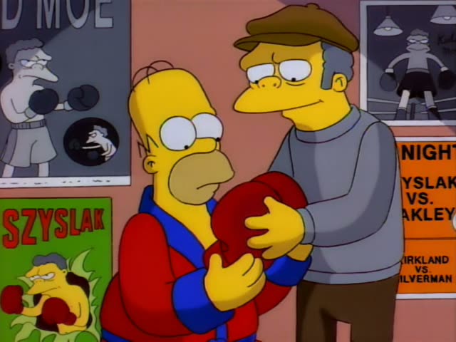 Homer and an older man in a flat cap and grey sweater stand in a gym lined with boxing posters, including one…
