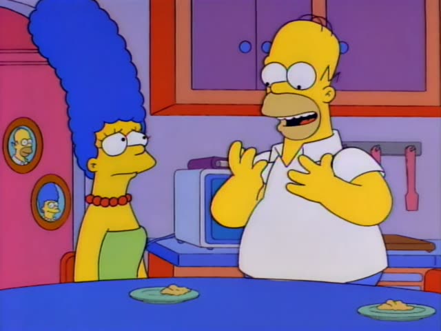 Marge Simpson sits at the kitchen table across from Homer Simpson, who is bald, heavy, and wears a white shirt
