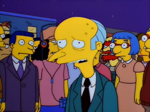 Mr. Burns stands at the front of a crowd in a teal jacket and black tie, with a large bald dome