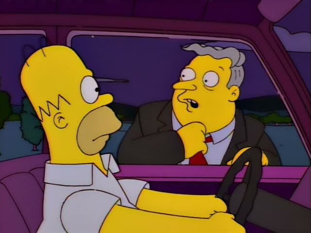 Homer Simpson drives a purple car while a grey-haired man in a brown suit and red tie sits beside him, talking and gesturing…