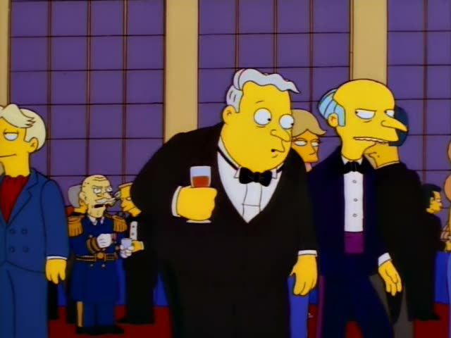 Mr. Burns stands at a formal party in a dark tuxedo beside a heavy, grey-haired man in a black tuxedo holding a small glass…