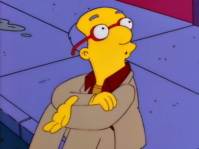 Milhouse stands with his arms crossed on a city sidewalk beside Homer, who wears a light blue shirt and has a prominent belly