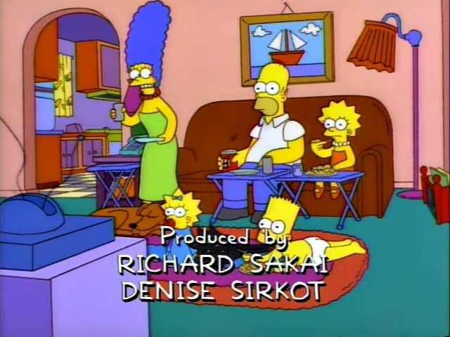 Homer, Lisa, Bart and Maggie sit in the pink living room eating from TV trays and a rug, with Santa's Little Helper…