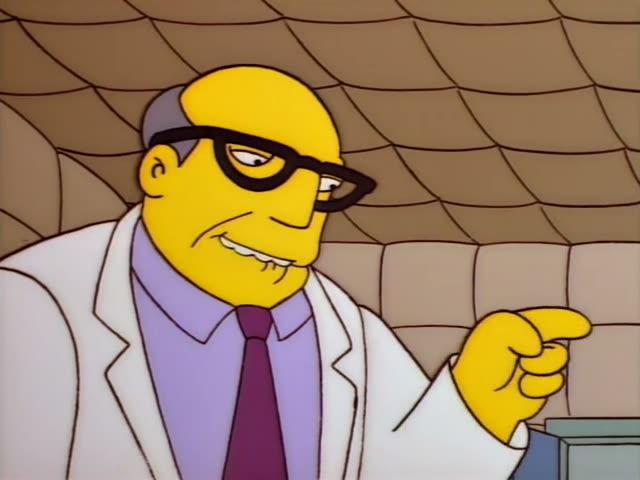 A bald, heavyset man with grey hair at the sides, black-rimmed glasses, a white lab coat, a lavender shirt and a maroon tie…