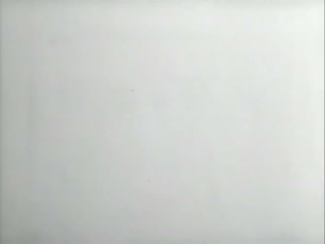 Ned Flanders appears in a white coat with buckles beside a bespectacled man in a lab coat who threads film onto a projector…