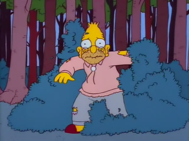 A heavyset yellow-skinned man with spiky yellow hair, round glasses, a bushy moustache, a pink sweater and torn grey…