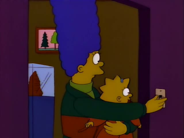 Marge Simpson stands in a doorway holding Maggie, the baby in an orange onesie with a pacifier and blue bow, while Marge's…