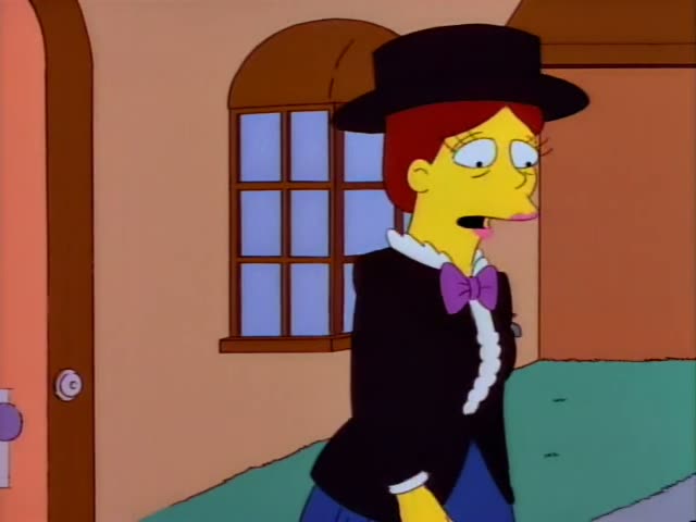 A woman with red hair under a black top hat, wearing a black jacket with a white ruffled collar and a purple bow tie, stands…