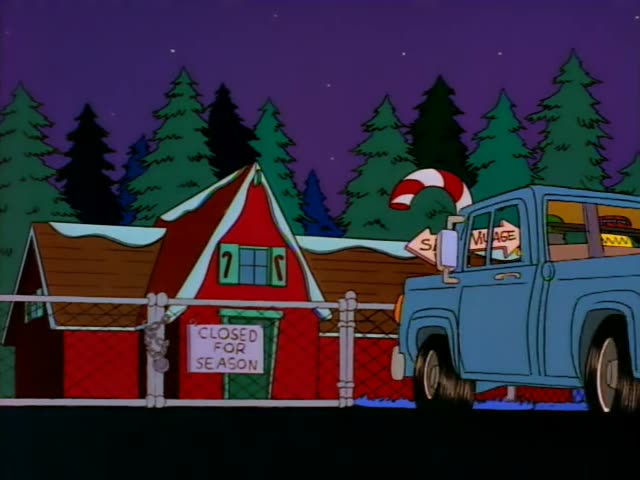 Grampa and a driver in a green cap and brown coat sit in a blue pickup truck that pulls up to the fenced red Santa's…