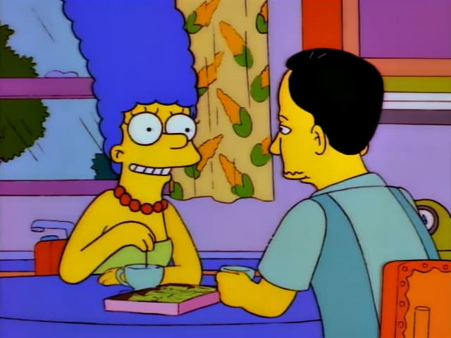 Marge sits at the kitchen table across from a thin man with neat black hair, a light blue shirt and suspenders, both…