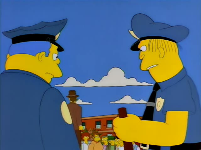 Chief Wiggum stands beside a second officer with a badge and a wooden mallet, while a man in a brown suit and fedora stands…