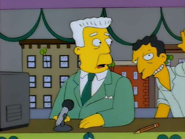 Kent Brockman sits at a studio desk with a microphone and pencil while a red-haired man in a red-and-white Sox jersey…