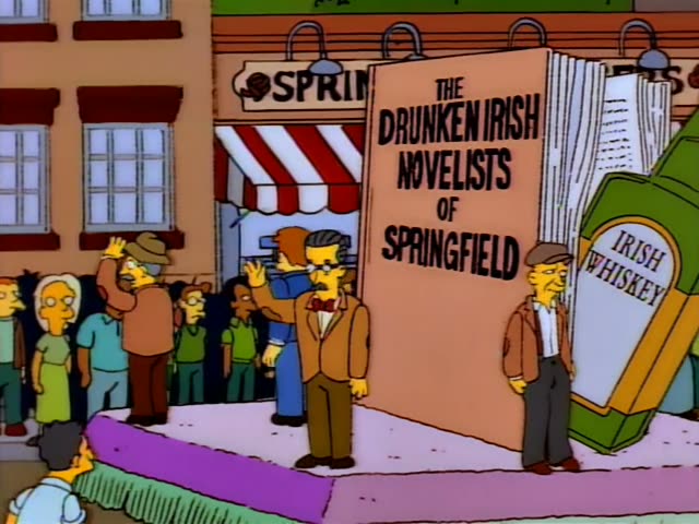 Grampa and Homer stand on a purple parade float shaped like a giant book titled 'The Drunken Irish Novelists of Springfield'…