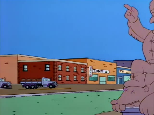 Chief Wiggum and Carl sit in a white police car outside Springfield County College, while a stitched pink figure…