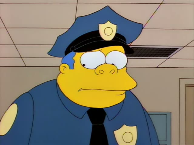 Chief Wiggum first appears in a close-up under his blue cap, looking off to the side and then speaking with his mouth open