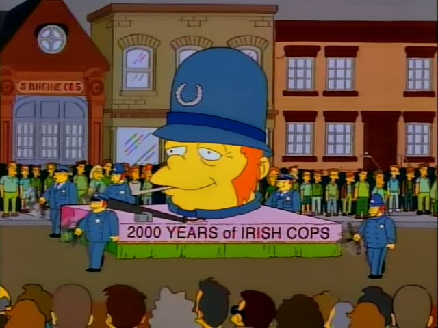 During a street parade past a fire station, a float shaped like a giant police officer's head…