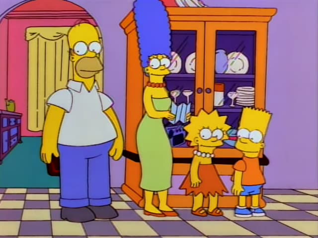 Homer, Marge, Lisa and Bart stand together in the kitchen beside an orange china cabinet, with Homer on the left and Marge…