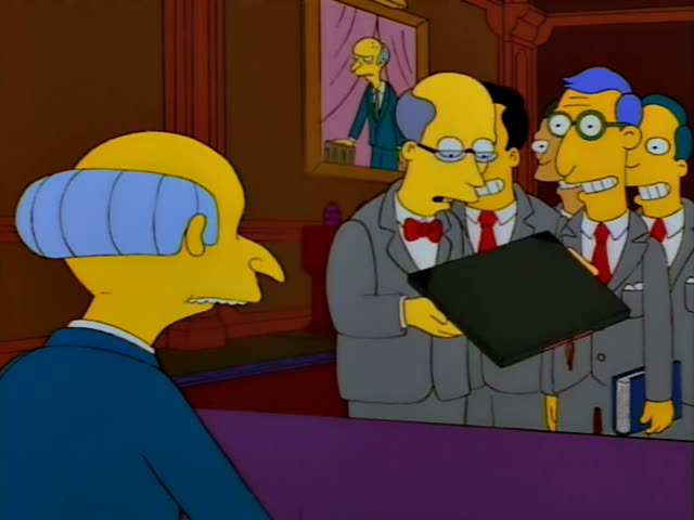 Mr. Burns sits at a purple desk in his office while a row of identical grey-suited men with red ties stands before him…