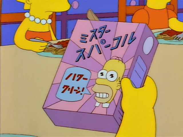 Bart sits at the dinner table with a plate of spaghetti and a fork, staring wide-eyed and stunned at a box held up in front…