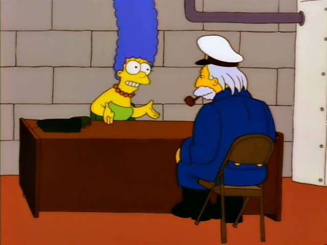 Marge Simpson leans on a wooden desk in a grey brick room while an unnamed old man with a white beard, sea captain's cap…