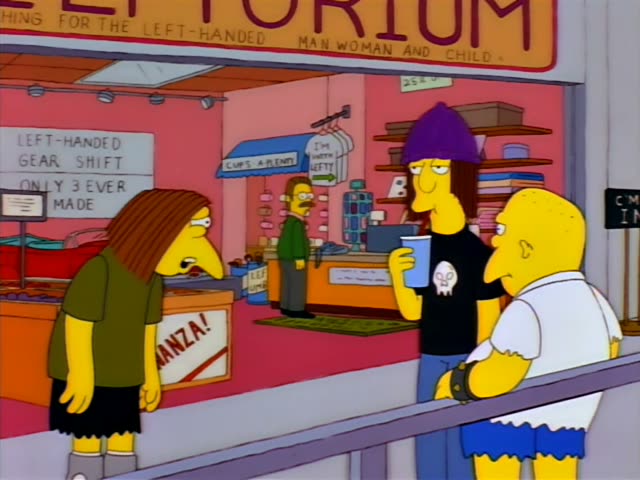 Homer leans on a railing beside a purple-haired man in a black skull t-shirt and a long-haired woman in an olive top…