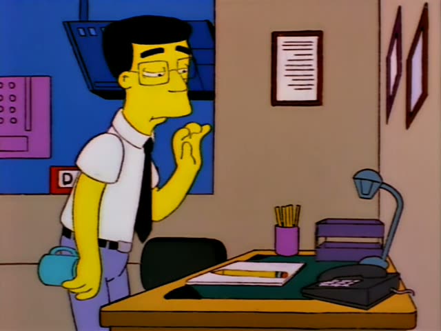Smithers stands at a desk in a nuclear plant office, then sits and leans on his elbow while holding a blue mug…