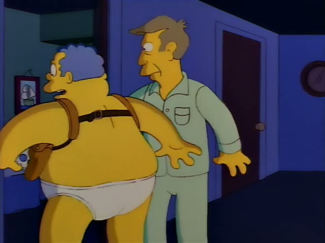 A heavy, bare-chested man in white briefs with a brown holster harness and blue-grey hair stands in a dim bedroom…