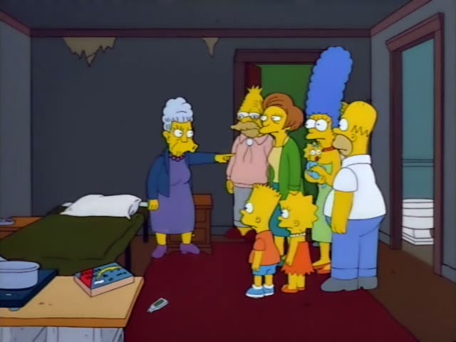 Homer, Marge with her tall blue beehive holding baby Maggie, Bart, Lisa and Grampa with white tufts of hair stand…