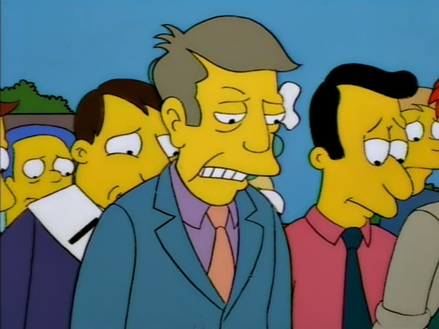 Principal Skinner stands in an outdoor crowd under a clear blue sky, with Mr. Burns beside him in a navy suit and red tie…