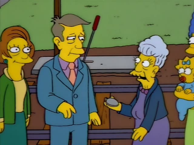 Principal Skinner stands on a wooden railway platform beside an elderly white-haired woman in a purple dress…