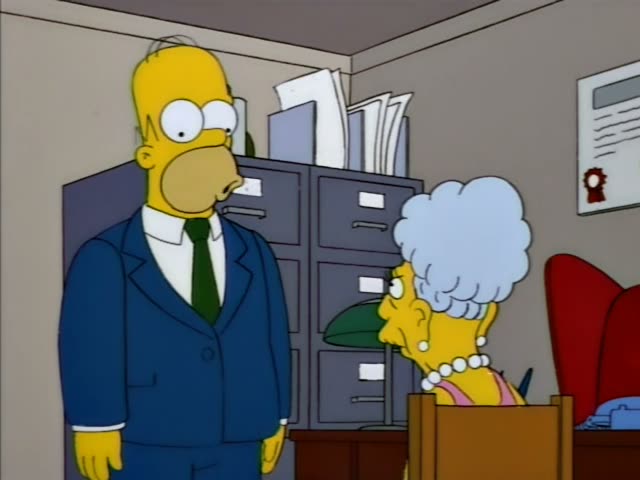 Homer stands in an office beside a grey filing cabinet while an elderly woman with a tall blue-grey beehive, pearl necklace…