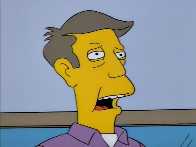 Principal Skinner stands at a wooden podium with a microphone before a red curtain, beneath a banner…
