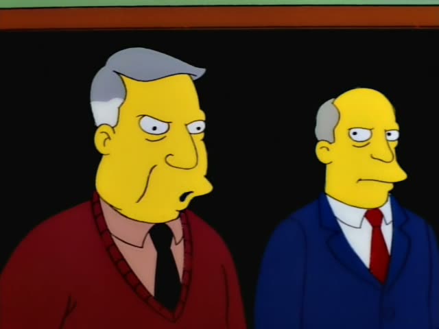 Mrs. Krabappel stands beside an older grey-haired man in a red sweater and black tie, while a bald man in a blue suit…