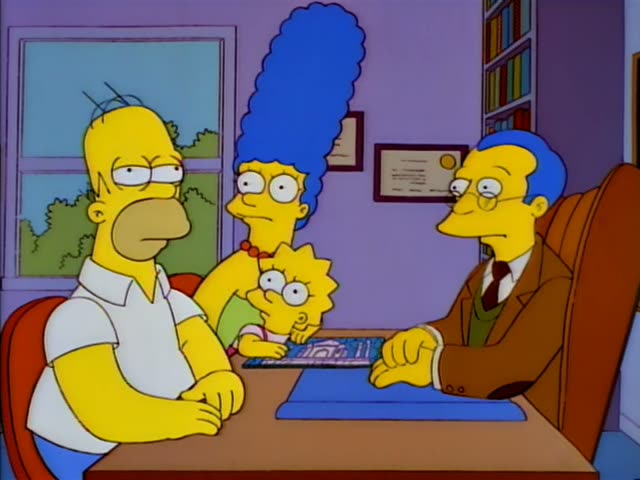 Homer sits at a desk beside Marge and Lisa, a small girl with spiky hair, who holds a small blue-and-white pamphlet