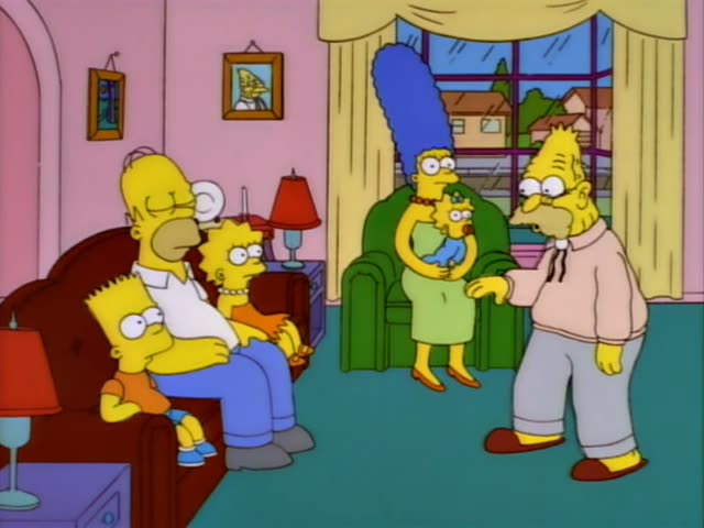 Homer, Bart, and Lisa sit together on a brown couch while Marge stands behind a green armchair holding Maggie, all watching…