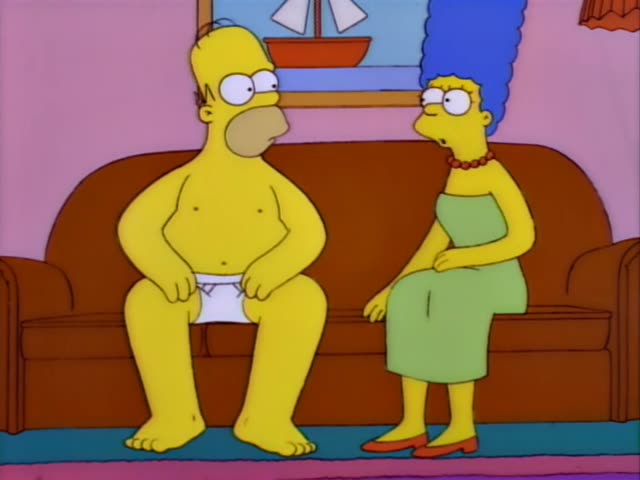 Homer sits on the brown couch in the living room next to Marge, who has a tall blue beehive, a red beaded necklace…