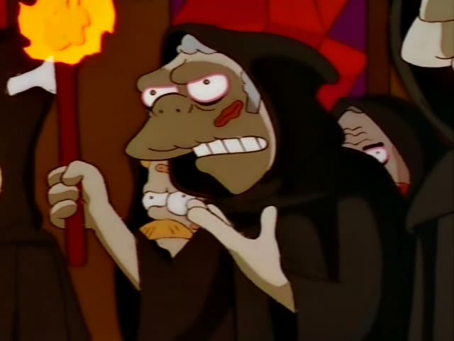 Several hooded figures in black robes with pale, lumpy faces stand in a dim, wood-paneled room lit by a torch with a bright…