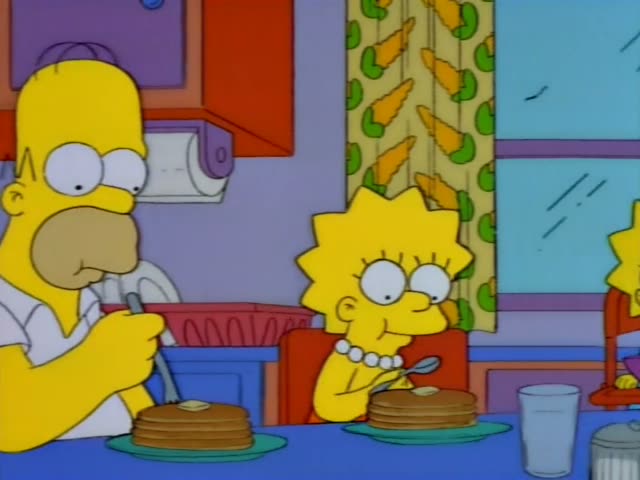 Homer, Lisa, Maggie, Marge and Bart sit around a blue-clothed kitchen table eating pancakes, with butter, syrup and a salt…