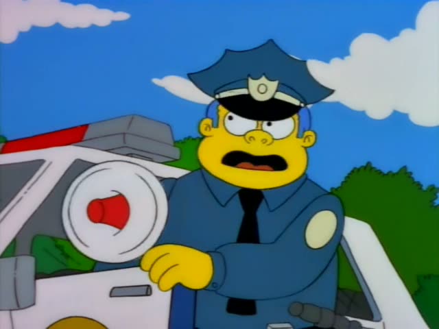 Chief Wiggum leans out of a white police car and shouts through a red-and-white megaphone