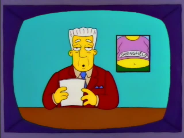 Kent Brockman sits at a desk in a TV studio with a Springfield poster behind him, reading from papers and glancing up…