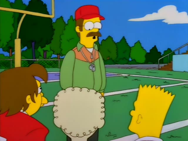 Ned Flanders stands on a football field with Bart and a brown-haired woman in red at the left edge