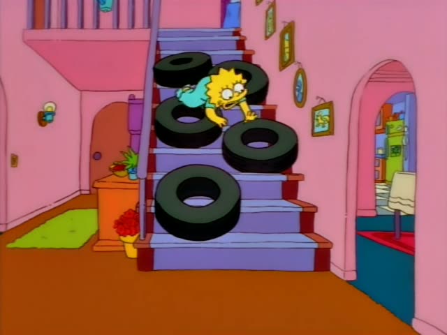 A little girl with spiky yellow hair in teal pajamas tumbles through a stack of black tires on a purple-carpeted staircase…