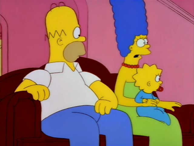 Homer, Marge, and baby Maggie sit on a red couch in a pink living room with Lisa and Bart standing by a bay window whose…