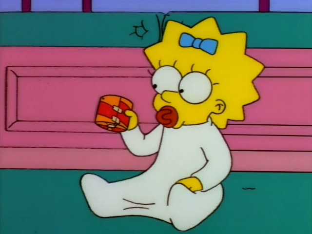 Maggie sits on a teal floor in front of a pink cabinet, holding a red and orange wrapped gift and waving it outward