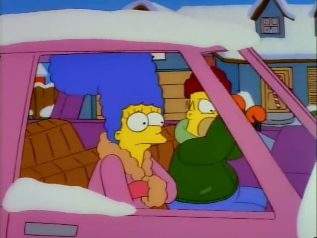 Marge Simpson sits in the passenger seat while Homer Simpson grips the steering wheel of a pink car parked on a snowy street…